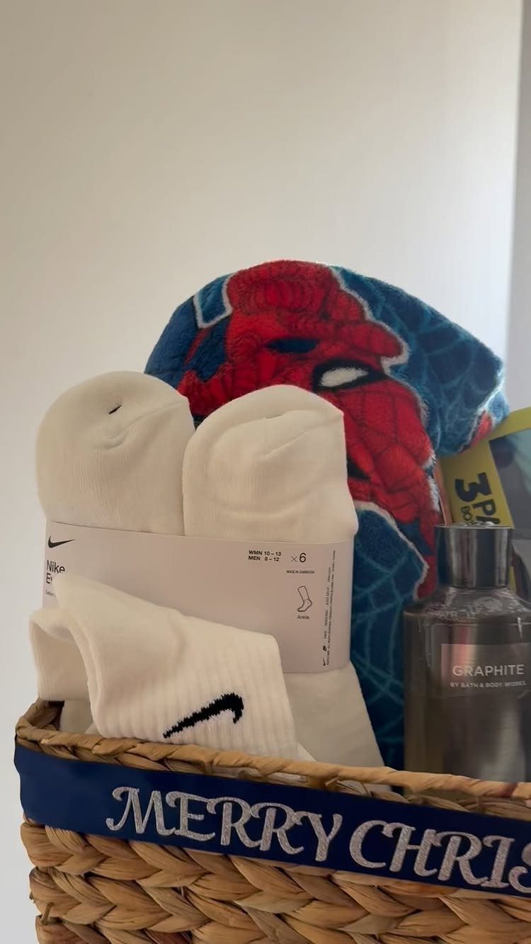Wicker gift basket with Nike socks, Spider-Man plush, and a grey bottle.