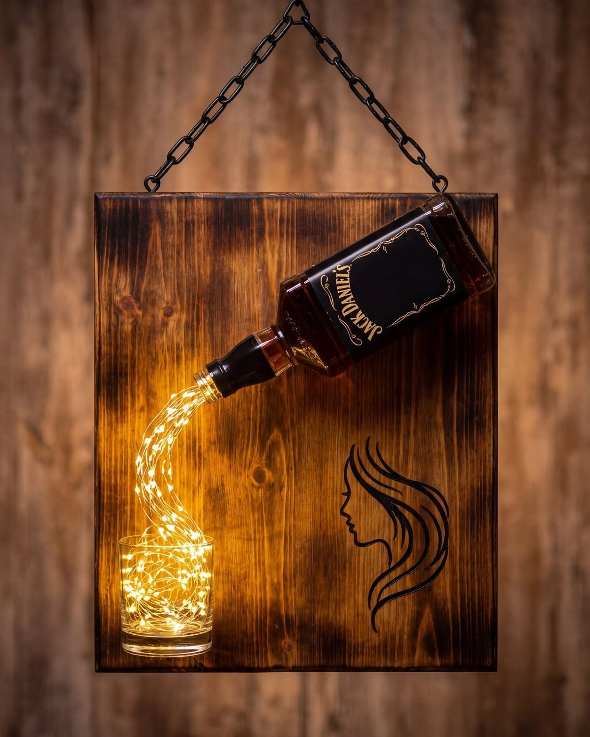 Whiskey bottle and glass on wooden board with glowing fairy lights and engraving