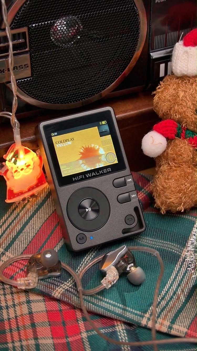 Digital music player and earphones on plaid fabric with a Santa teddy bear.