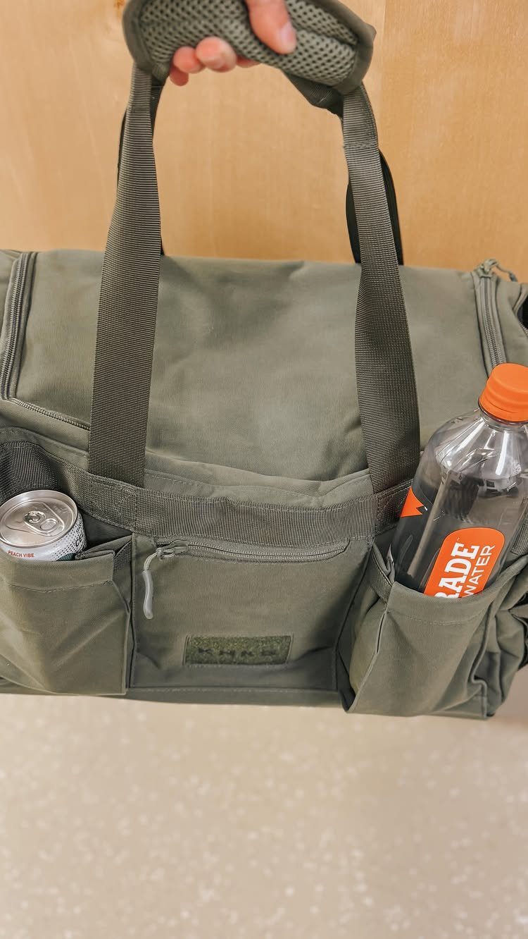 Olive green cooler bag with a can and orange sports drink in side pockets.