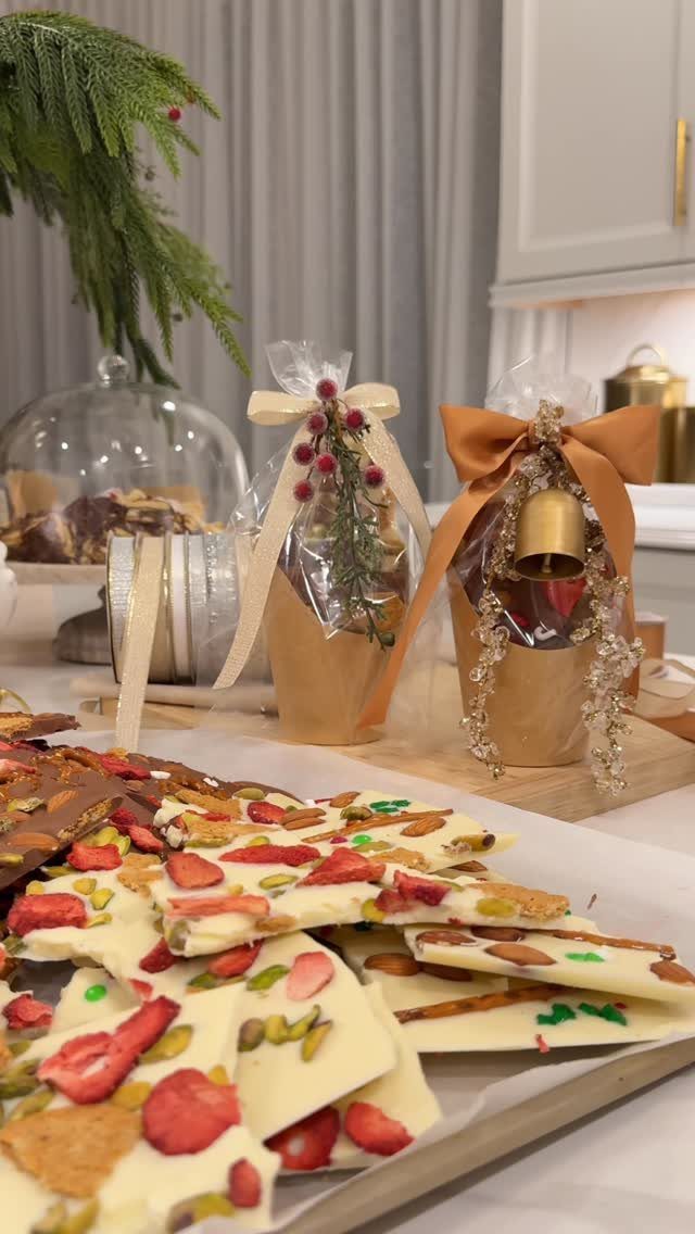 White chocolate bark with strawberries and pistachios next to wrapped holiday gift bags.