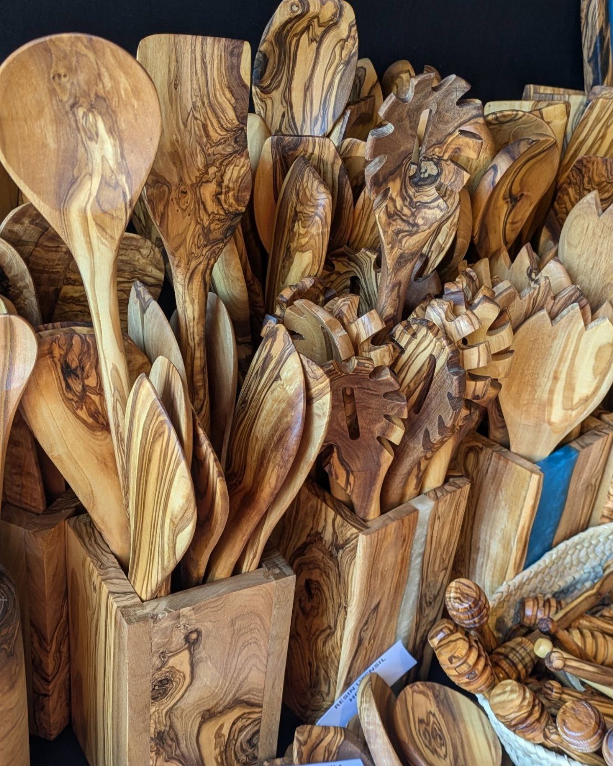 Handcrafted olive wood kitchen utensils stored in matching wooden square holders.