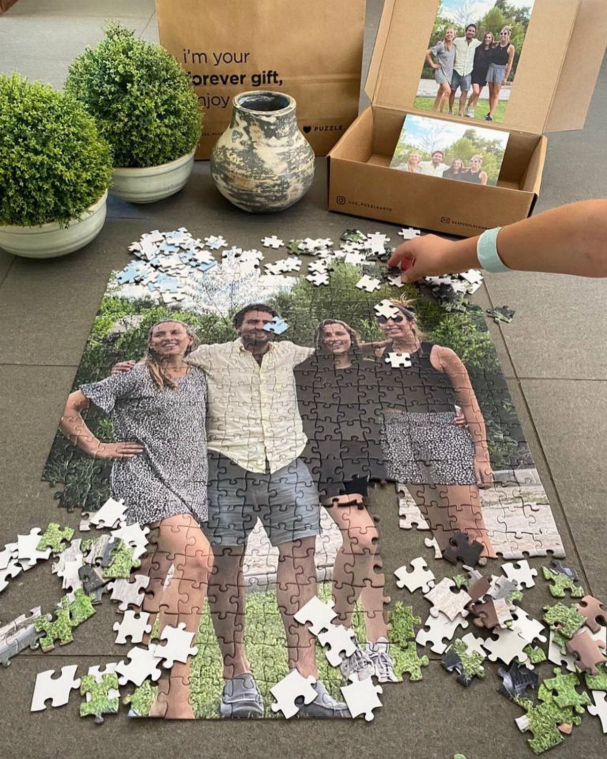Partially completed photo puzzle of a family on a grey tiled floor.