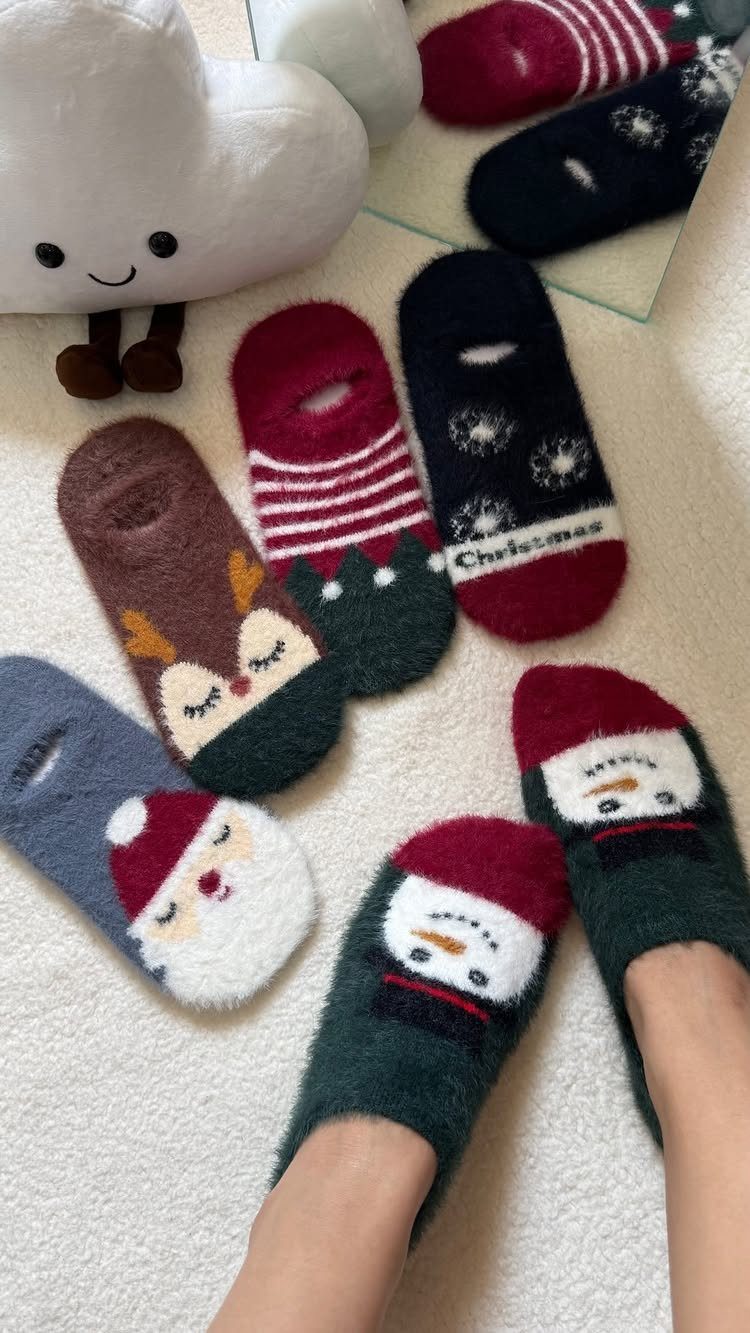 Fuzzy Christmas socks with reindeer, Santa, and snowman designs on white carpet.