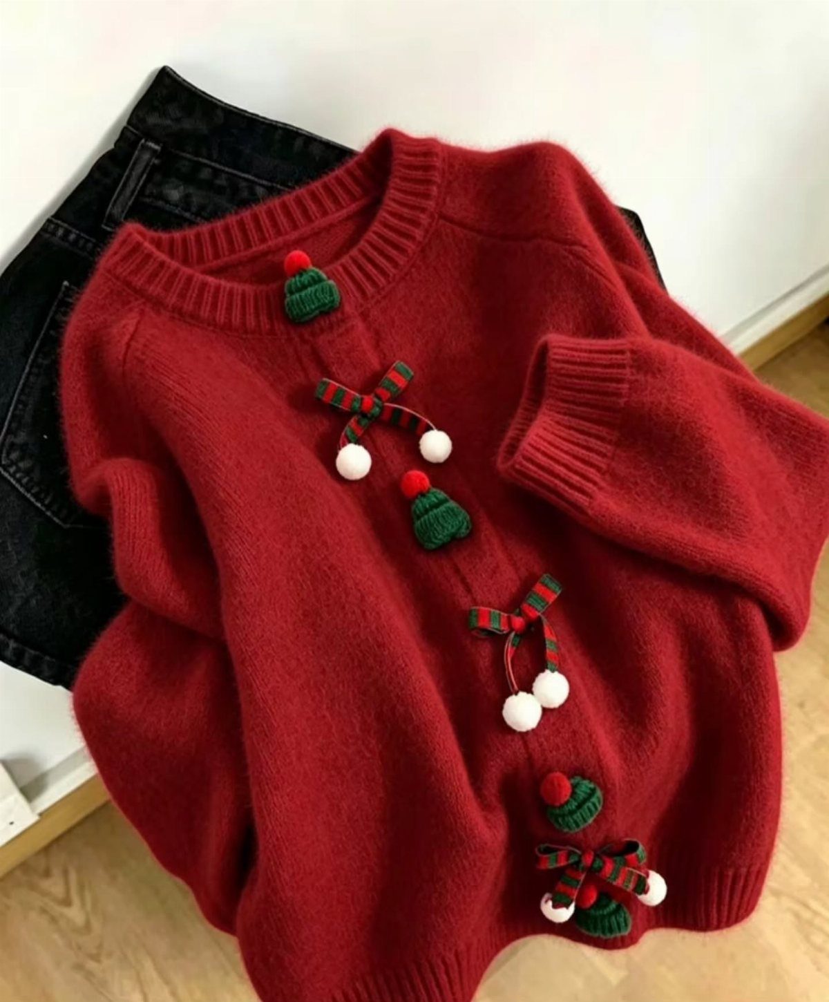 Red festive knit sweater with bows and hats on black denim jeans