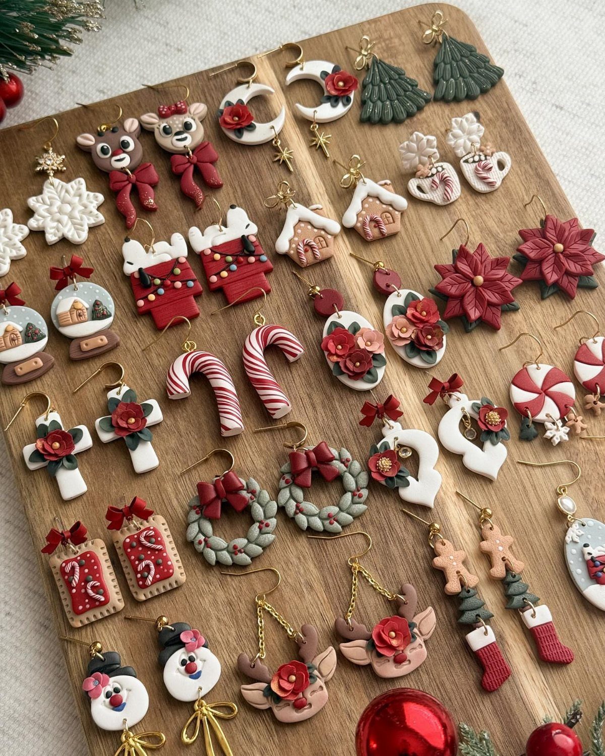 Handmade polymer clay Christmas earrings arranged on a light wooden board.