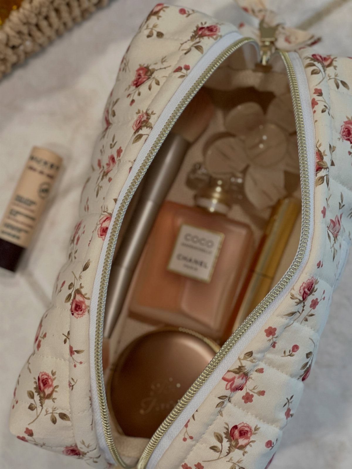 Floral quilted makeup bag filled with luxury perfume and gold beauty cosmetics