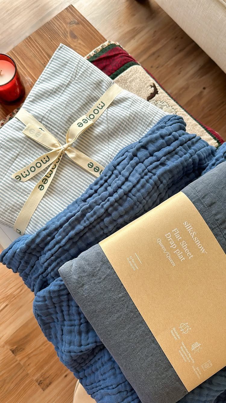 Folded fabric sheets in grey and blue tones tied with a cream ribbon.