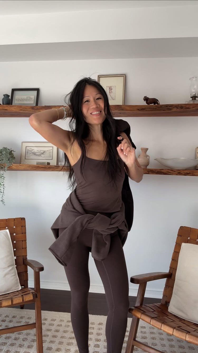 Woman wearing a dark brown athletic tank top and matching tight leggings indoors.