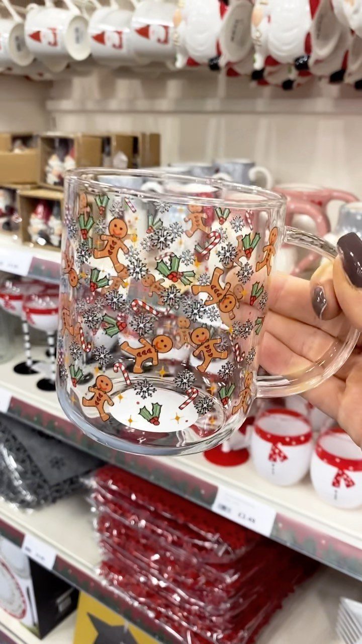 Clear glass mug with gingerbread men and snowflakes held in a store.