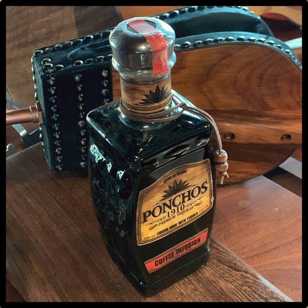 19 Coffee Fan Gifts for Every Budget and Brew Style 4 Ponchos Coffee Infusion liqueur bottle on a wooden table next to a studded case.