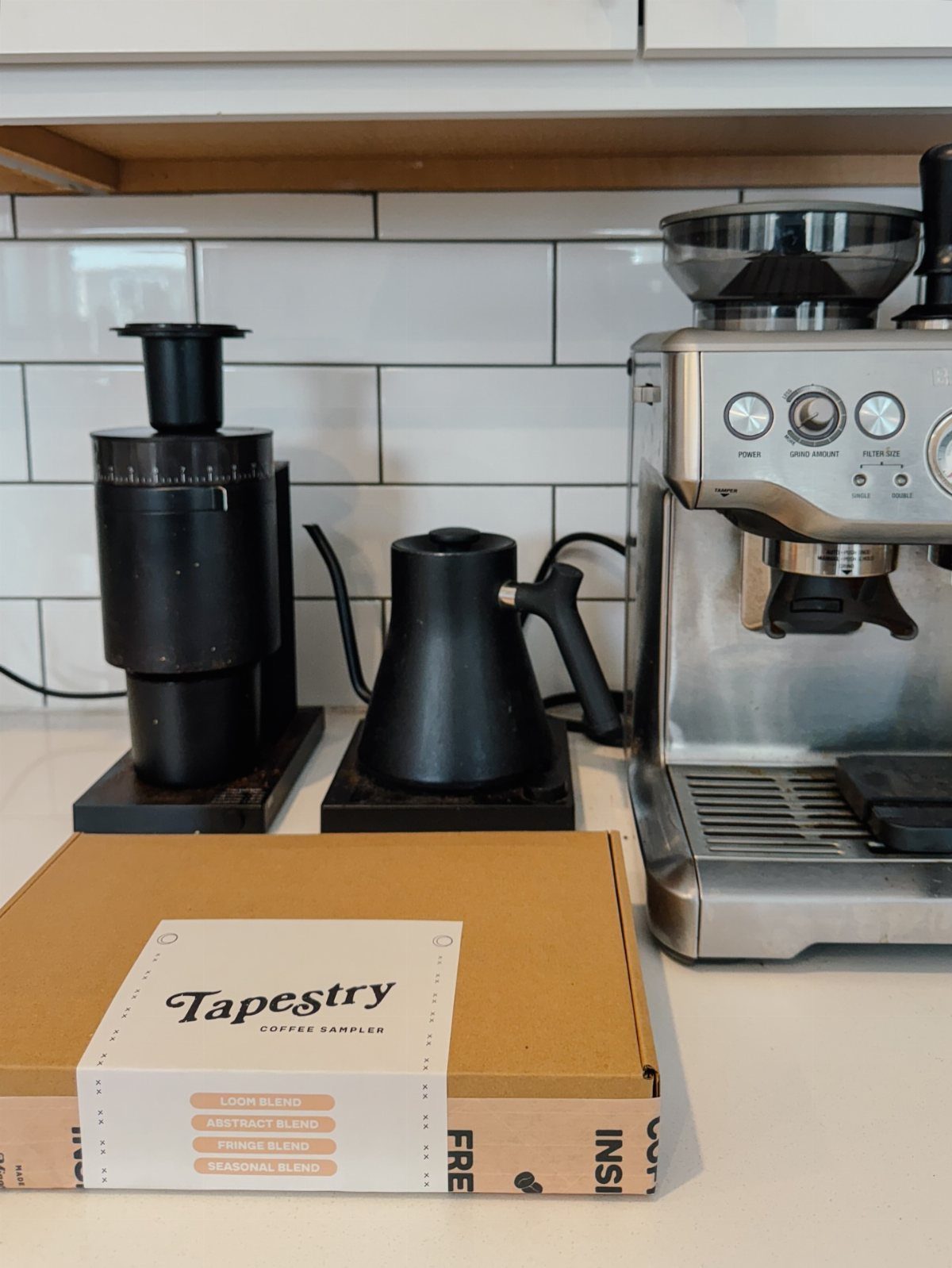 19 Coffee Fan Gifts for Every Budget and Brew Style 11 Tapestry coffee sampler box on a counter with an espresso machine and grinder.