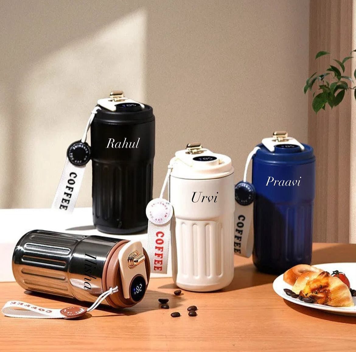 19 Coffee Fan Gifts for Every Budget and Brew Style 2 Four personalized travel mugs in various colors on a wooden table with pastries.