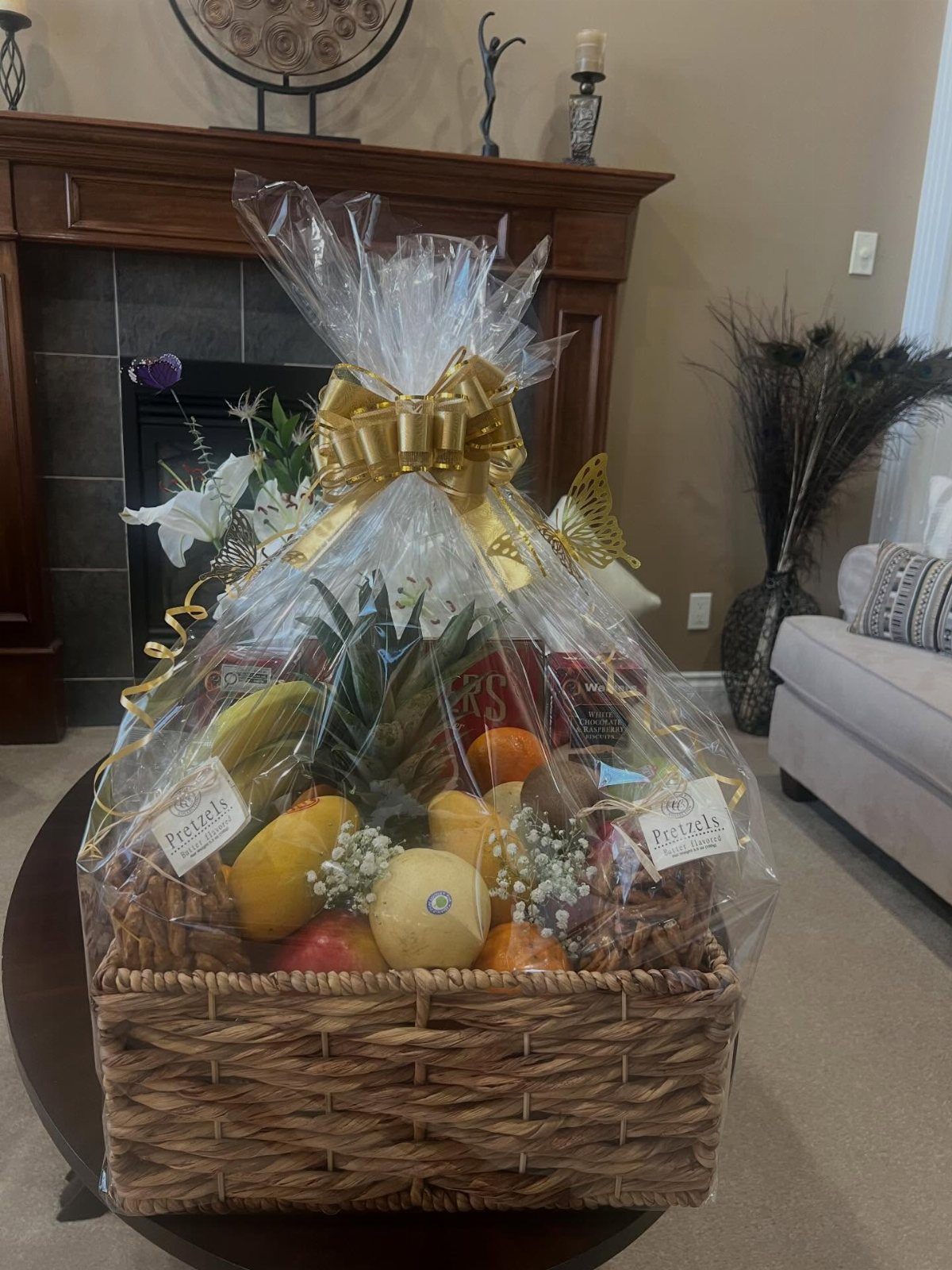 Fruit basket with pineapple and citrus wrapped in cellophane with a gold bow.