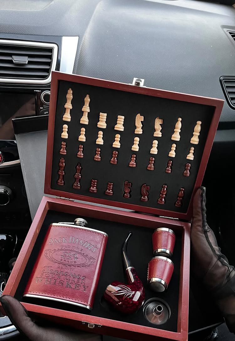 Red wooden gift set containing a chess set, whiskey flask, and smoking pipe.