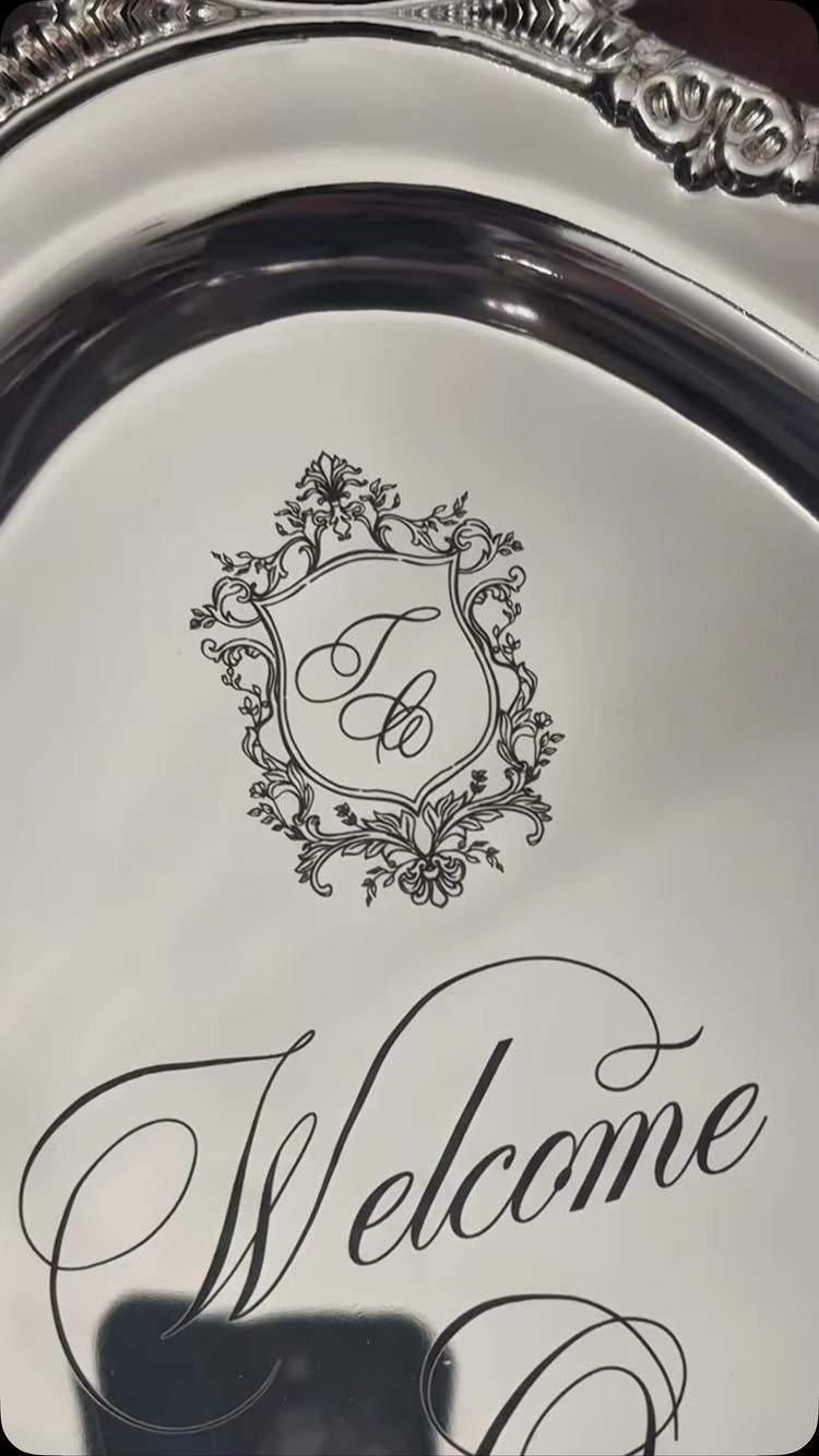 Silver tray with an engraved ornate crest and cursive Welcome text.