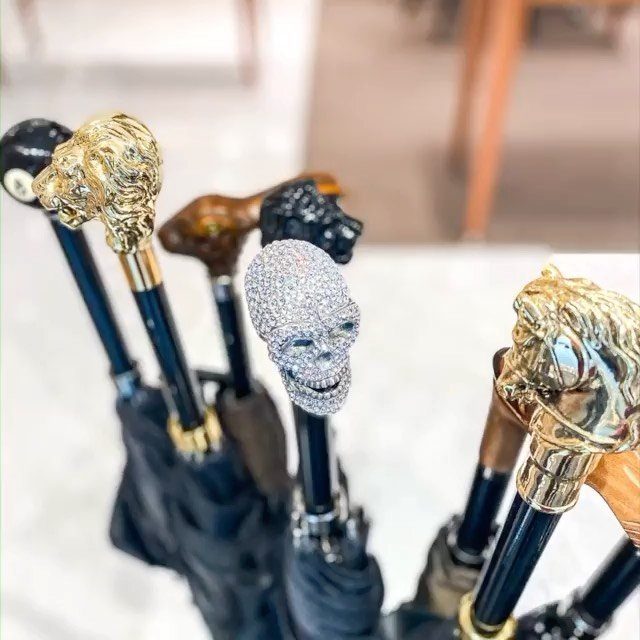 Luxury umbrella handles featuring gold lion heads and a crystal-encrusted silver skull.