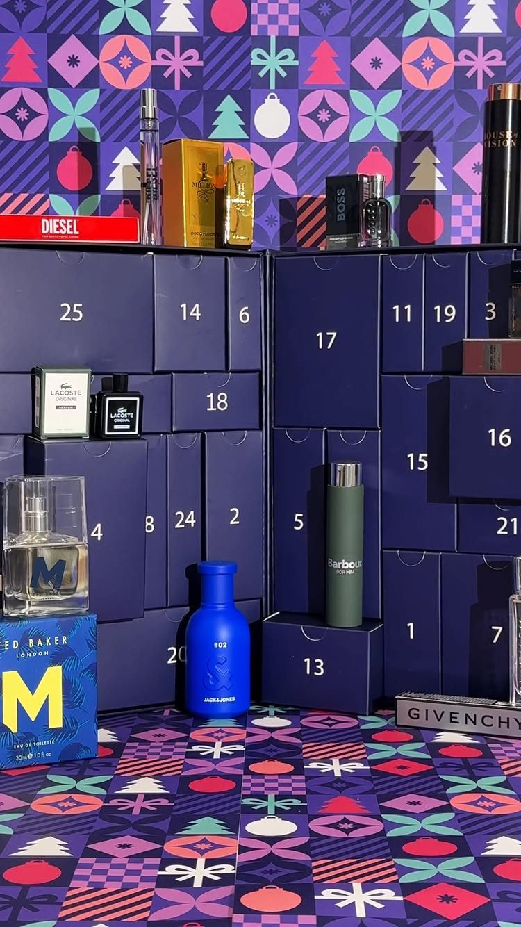 Advent calendar of blue boxes filled with men's fragrances against holiday patterns.