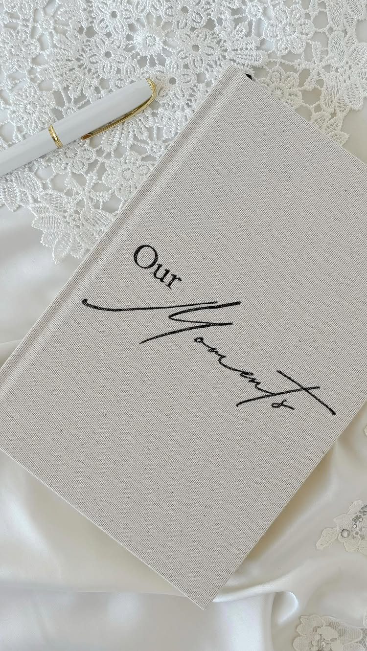 Beige linen journal with 'Our Moments' text on white lace and satin fabric.