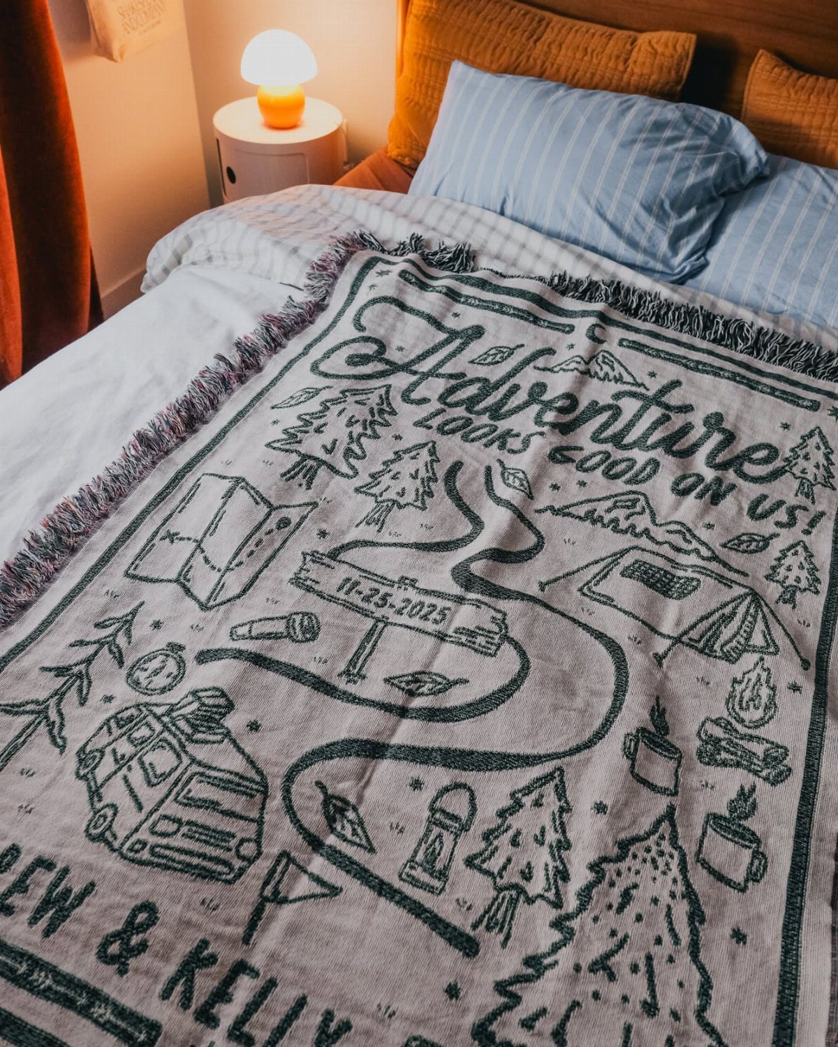 Customized woven blanket with adventure illustrations and names resting on a bed.
