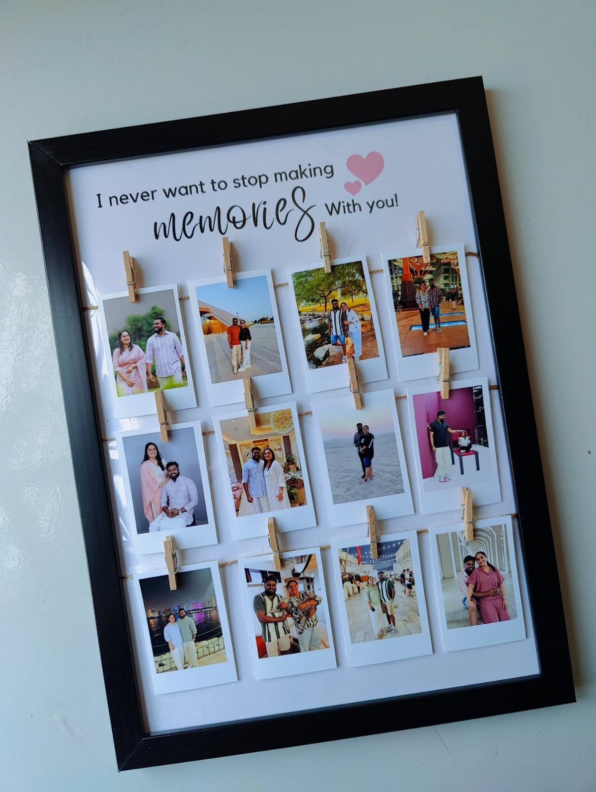 Framed collection of polaroid photos of a couple clipped to strings with clothespins