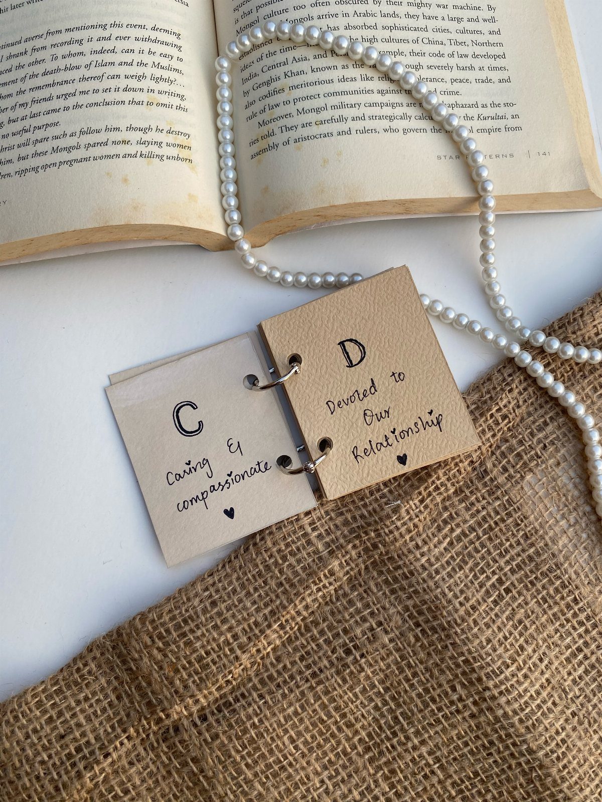 Handmade romantic gift cards with initials C and D next to a pearl necklace