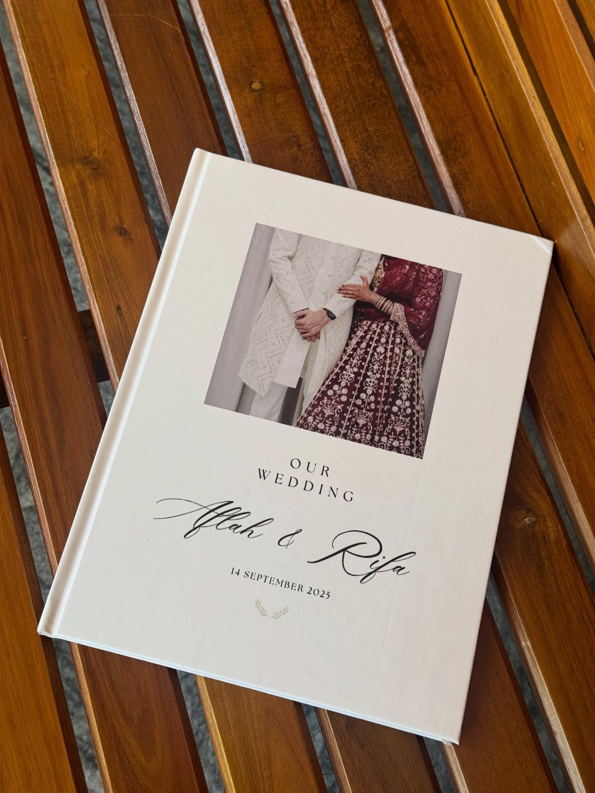 White wedding photo album with a couple's picture on a wooden slatted table