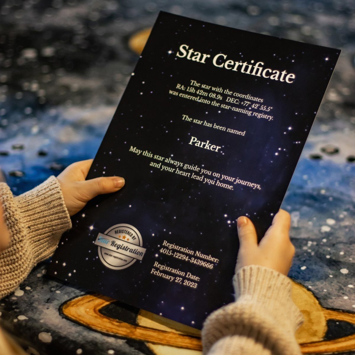 Hands holding a dark blue star naming certificate with white text and stars.