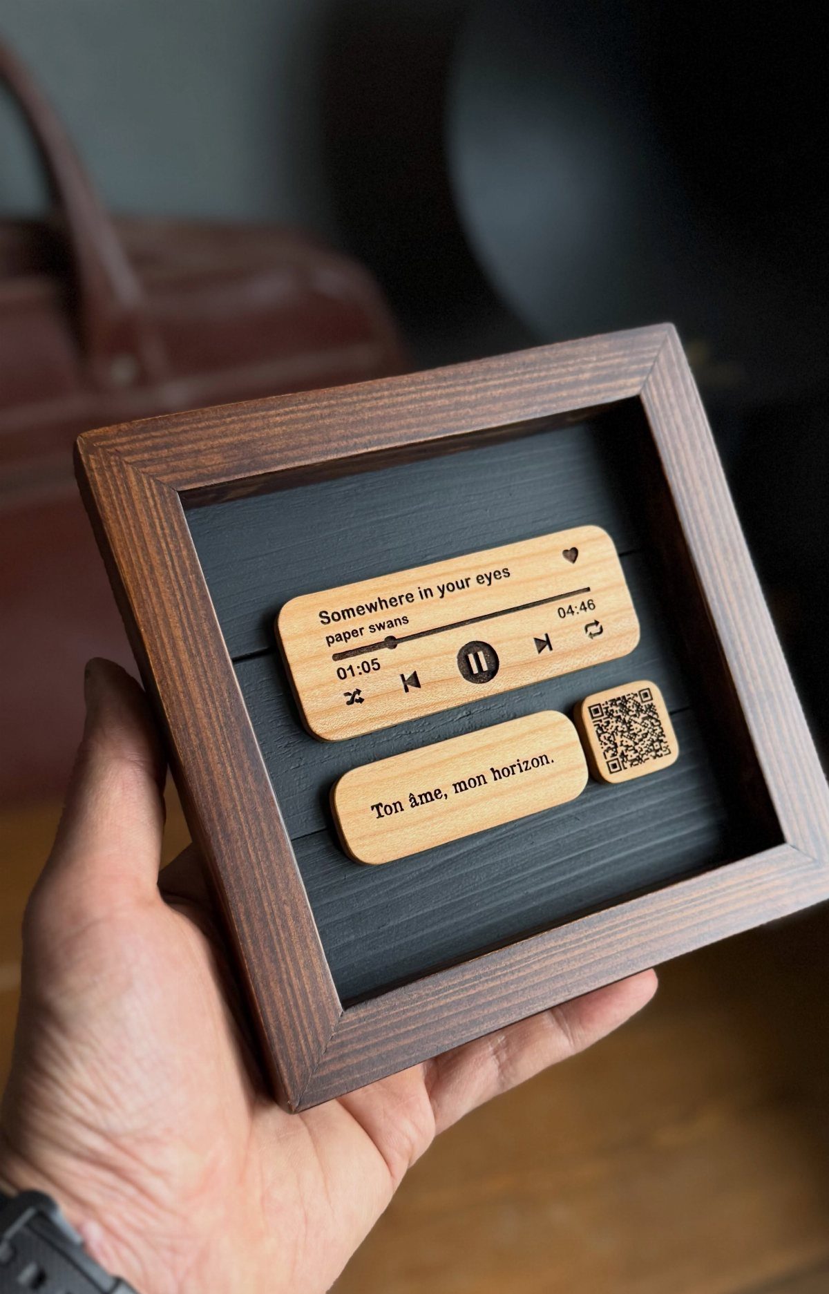 Wooden music player plaque in a frame held by a person's hand