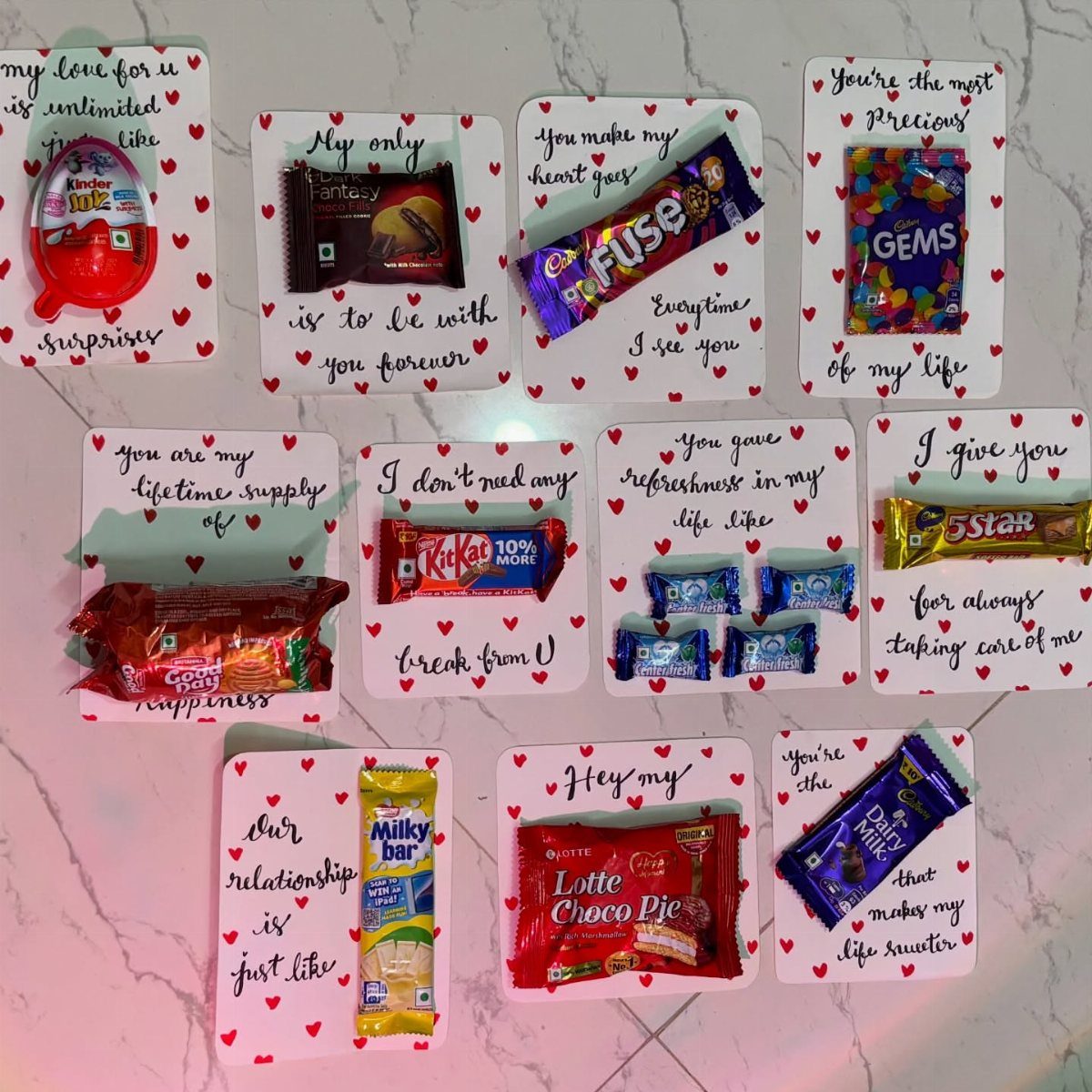 Handmade candy gift cards with romantic messages and red hearts on marble surface