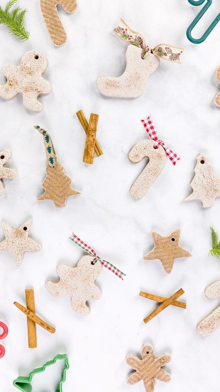 Handmade cinnamon ornaments in holiday shapes scattered on a white marble background.