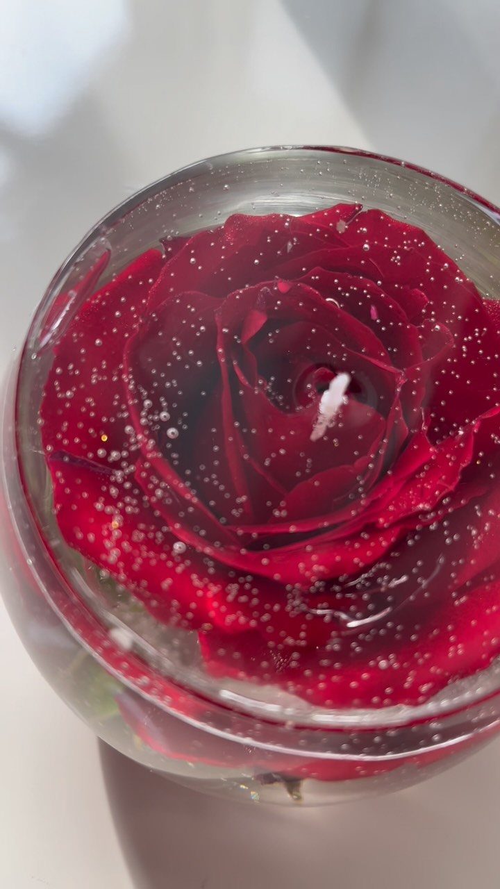 Red rose embedded in clear wax candle inside a glass jar