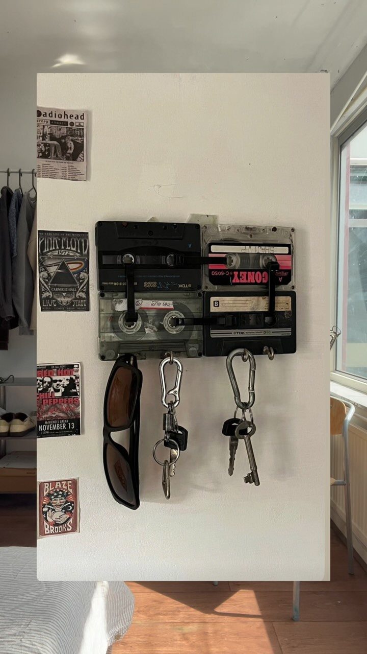 Cassette tape key holder on a white wall holding keys and sunglasses.