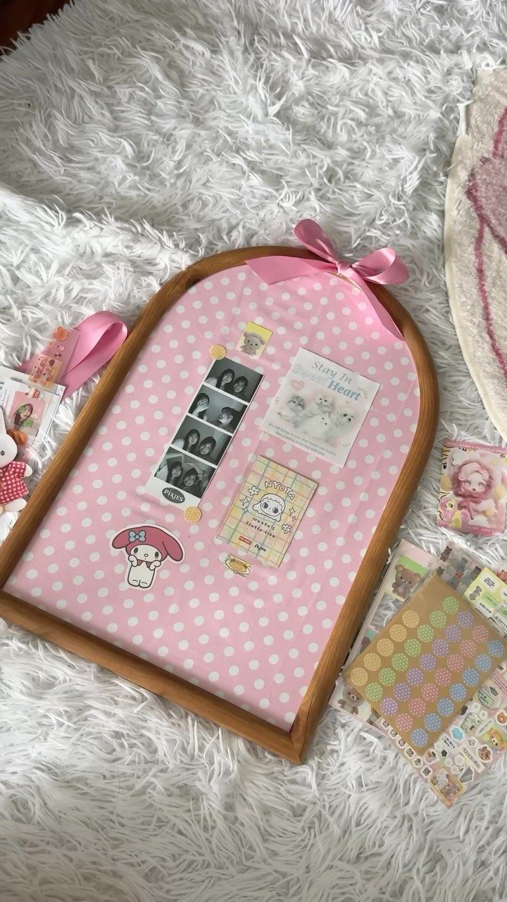 Arched wooden picture frame with pink polka-dot background and small personal photos.