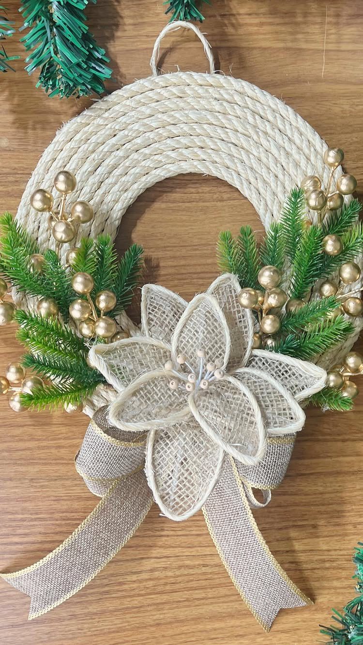 Rope wreath decorated with green pine, gold berries, and a burlap flower bow.