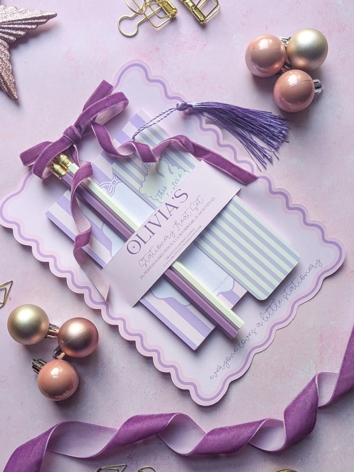 Personalized stationery set with purple striped notebooks and pencils tied with a ribbon.