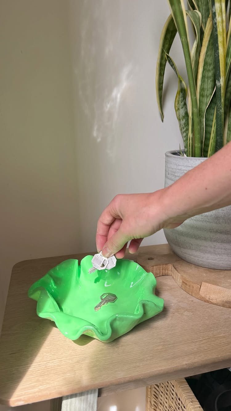 Hand placing a key into a bright green wavy resin trinket dish
