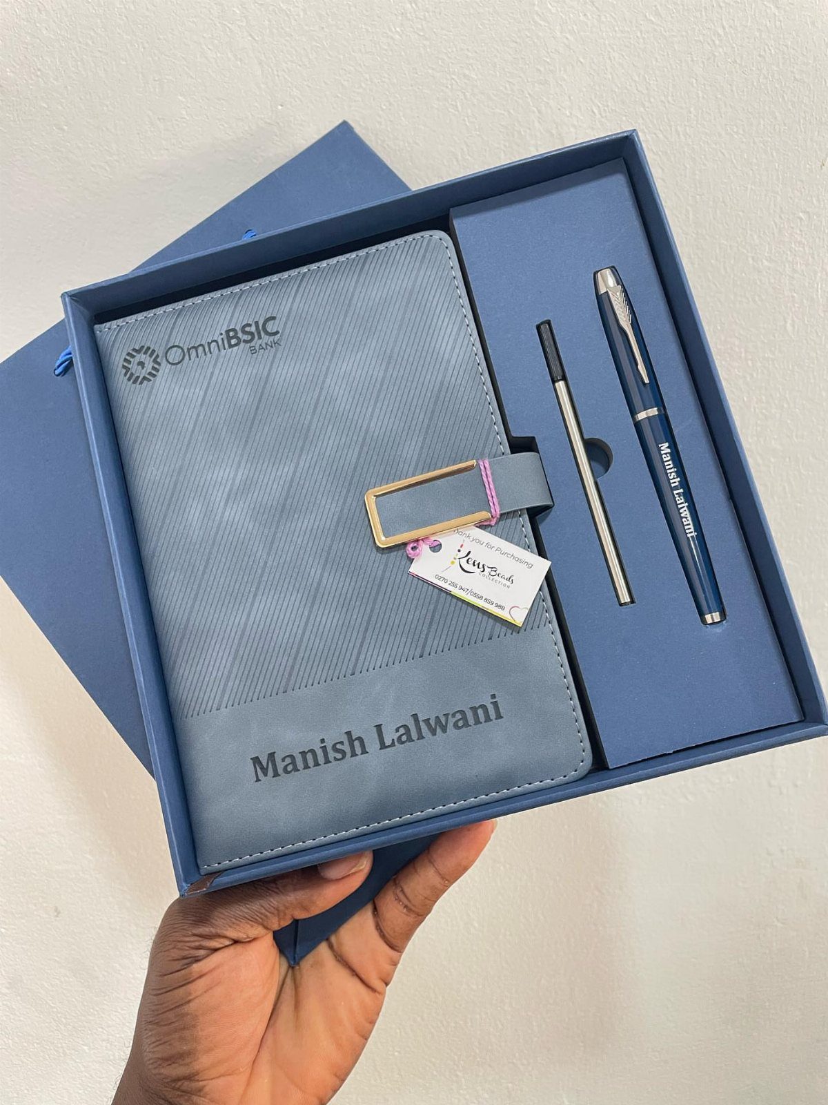 Blue customized notebook and pens in a matching gift box held by a hand
