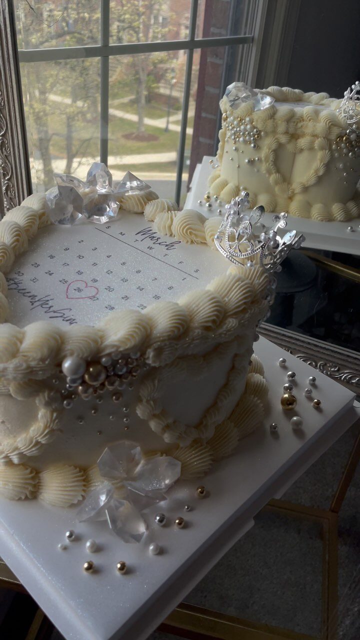 White frosted cake with a March calendar printed on top and pearl decorations.