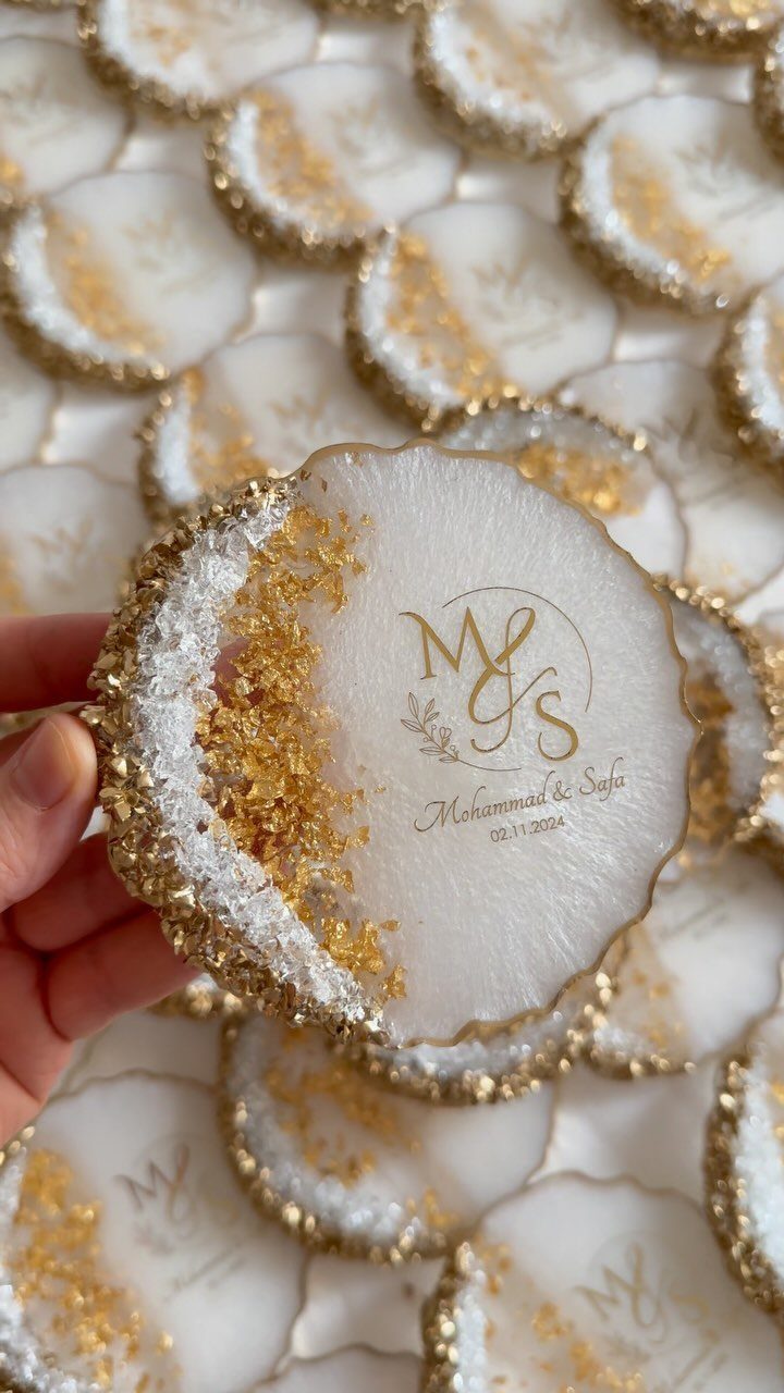 White resin coaster with gold foil edges and personalized gold lettering held by hand.