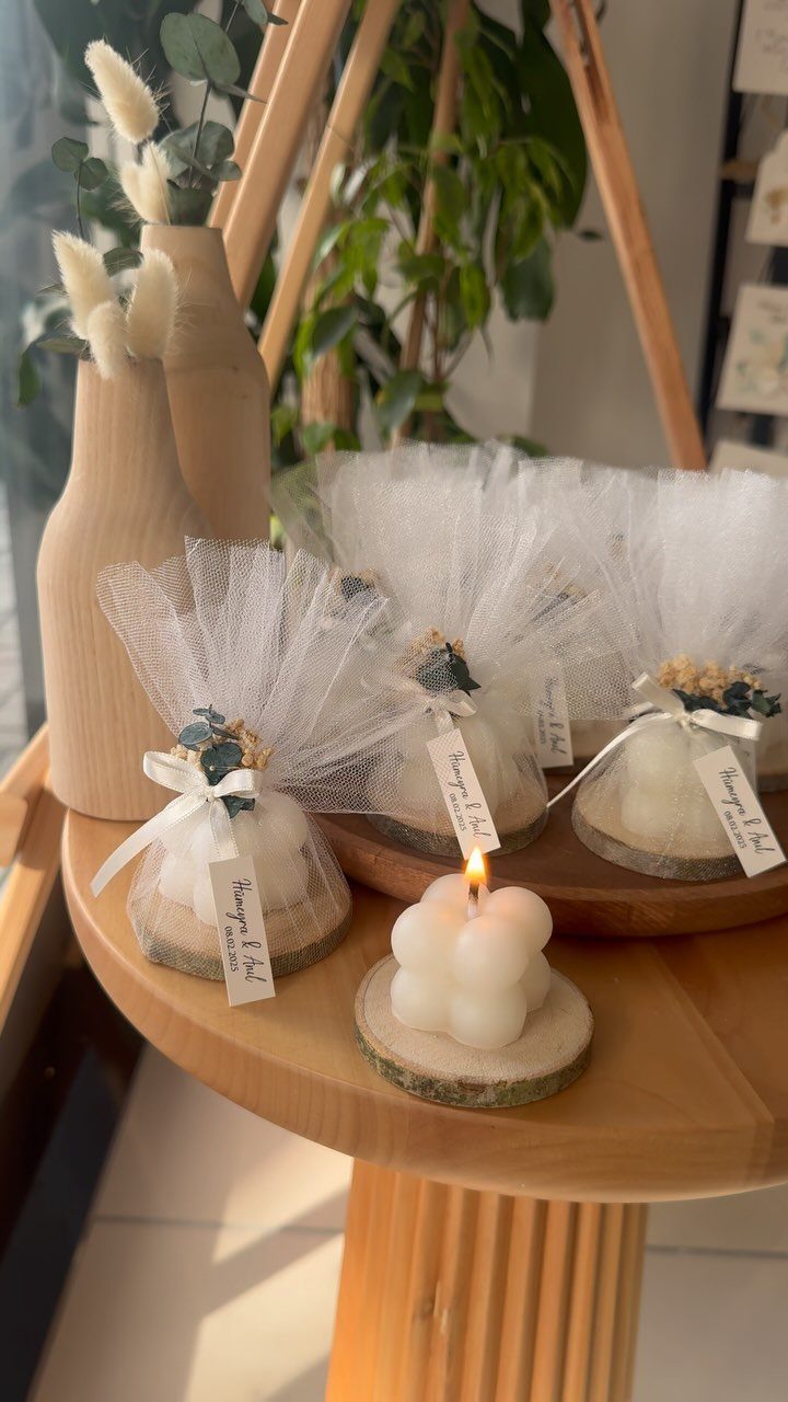 White bubble candles on wooden slices, some wrapped in tulle with ribbons.