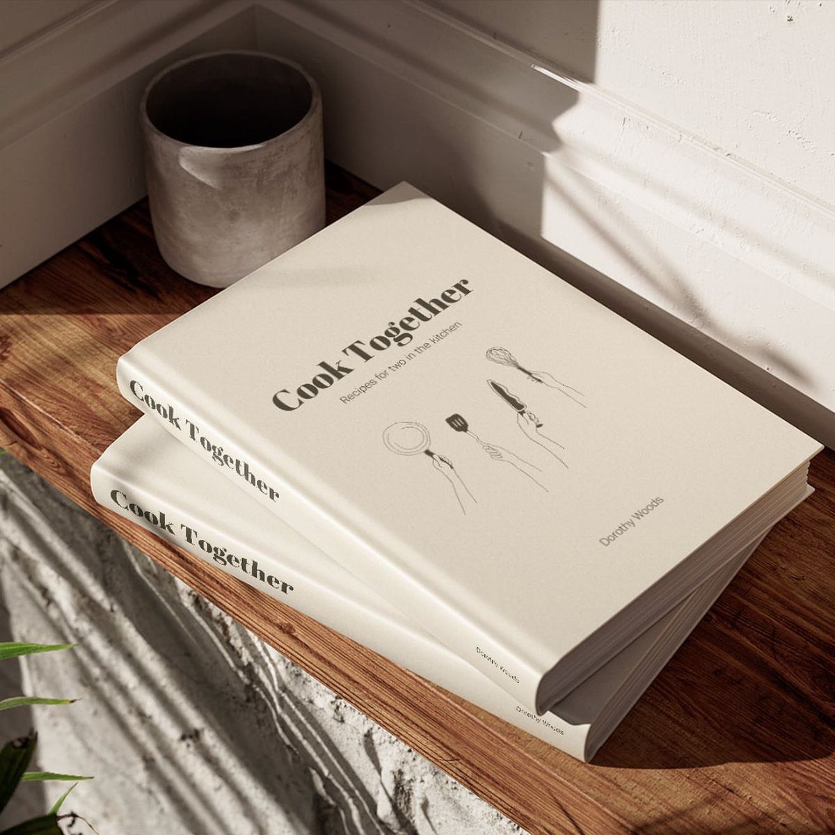 Two white Cook Together cookbooks stacked on a rustic wooden shelf.