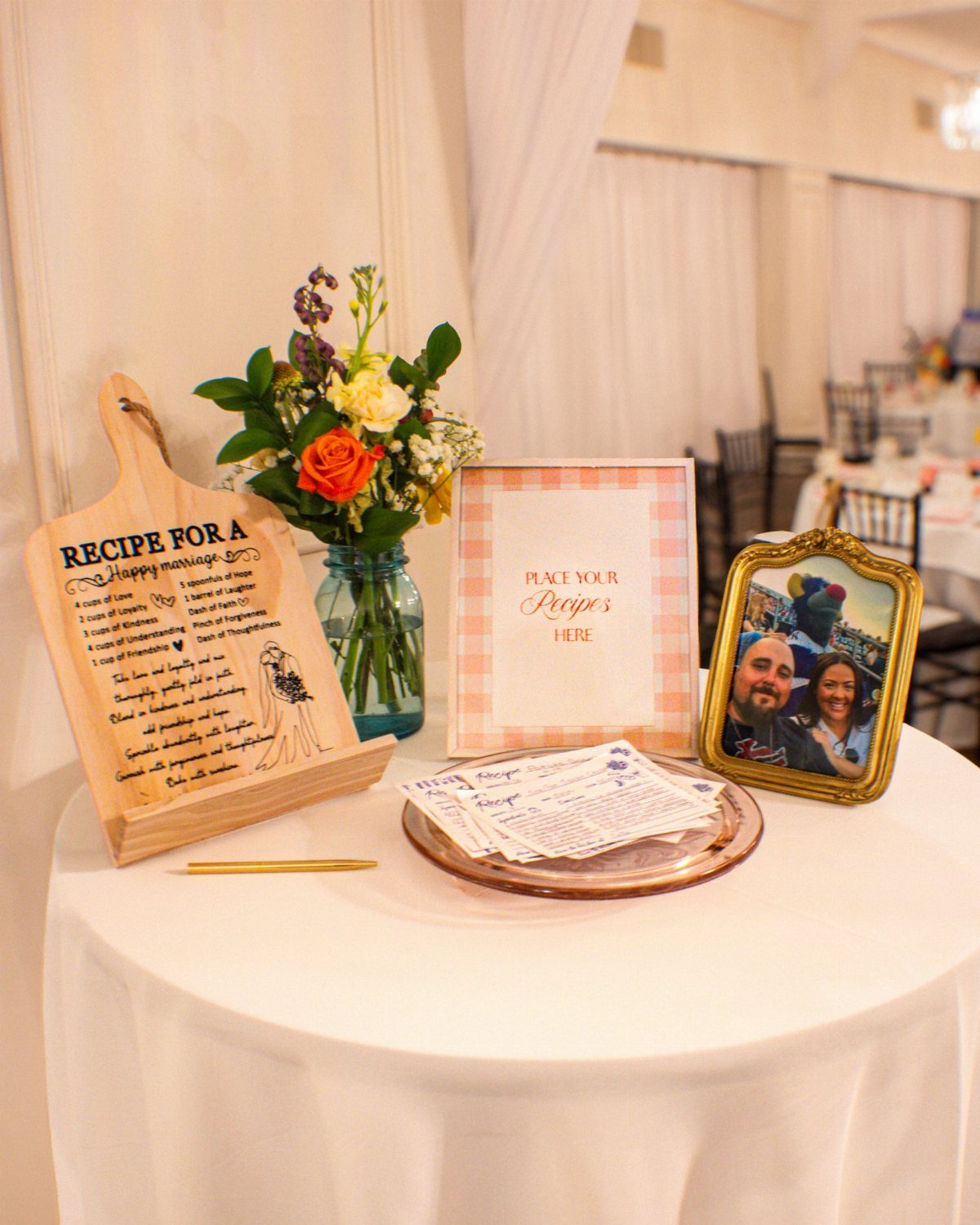 Wooden cutting board with marriage recipe next to flowers and couple's photo.