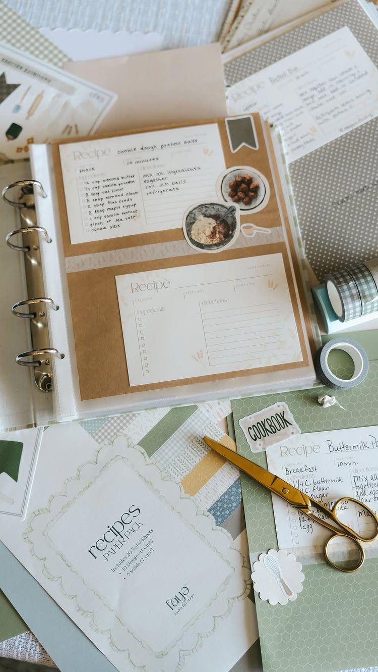 Handmade recipe binder with handwritten cards, gold scissors, and scrapbooking supplies.