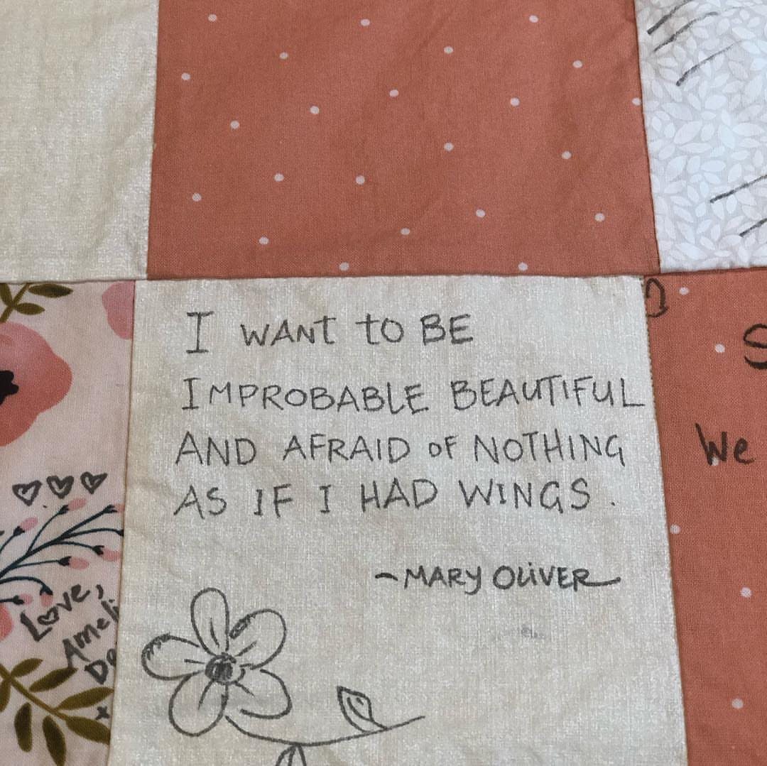 Handmade fabric quilt square with a handwritten Mary Oliver quote and flower drawing.