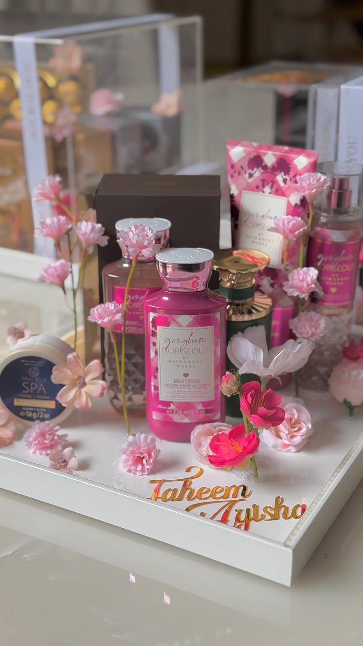 Beauty gift set with pink bottles and flowers on a personalized white tray
