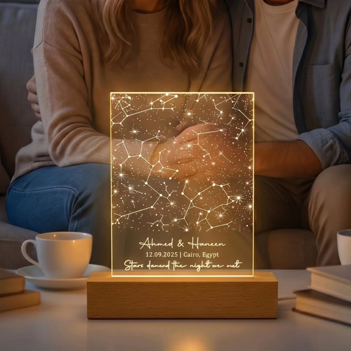 Illuminated acrylic star map plaque on wooden base with a couple in background
