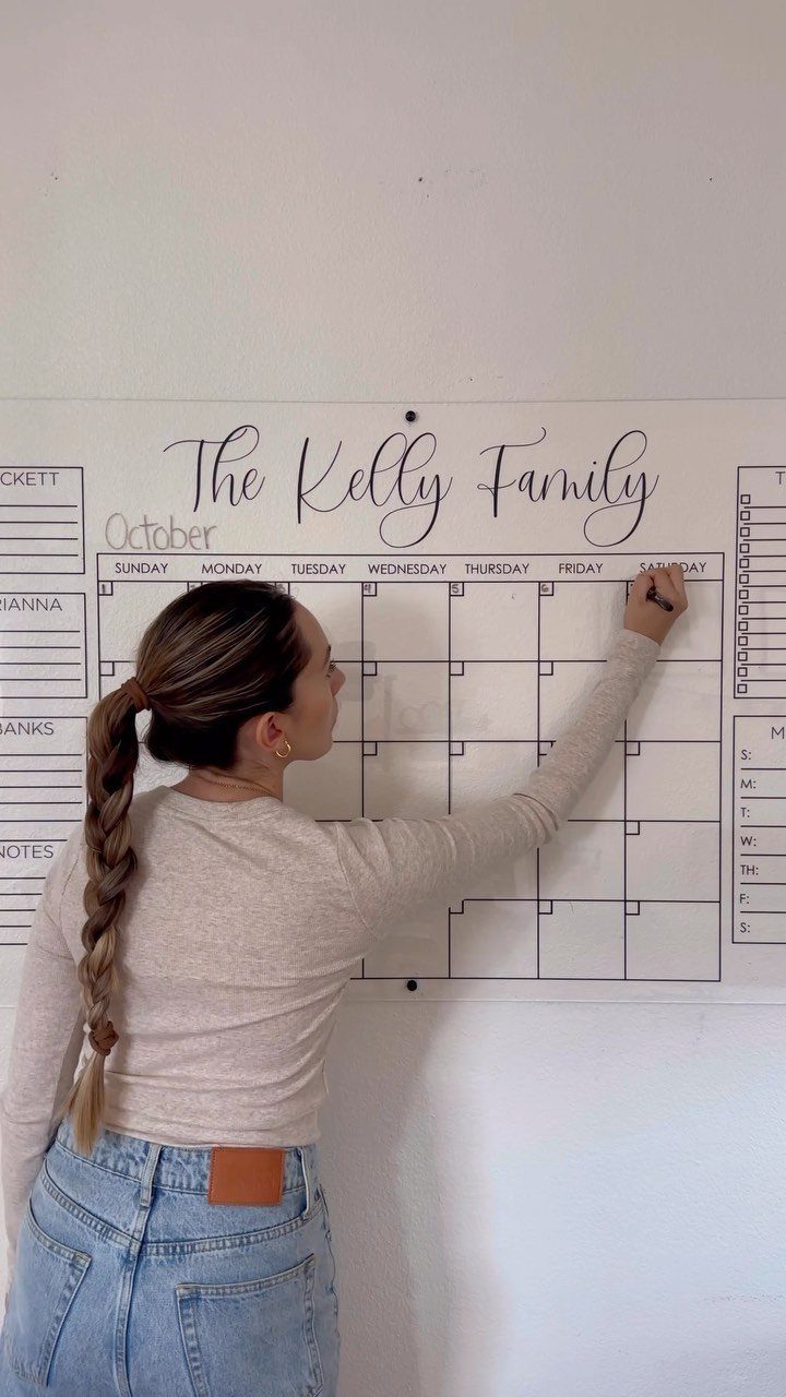 Woman writing on a large white wall calendar for The Kelly Family.