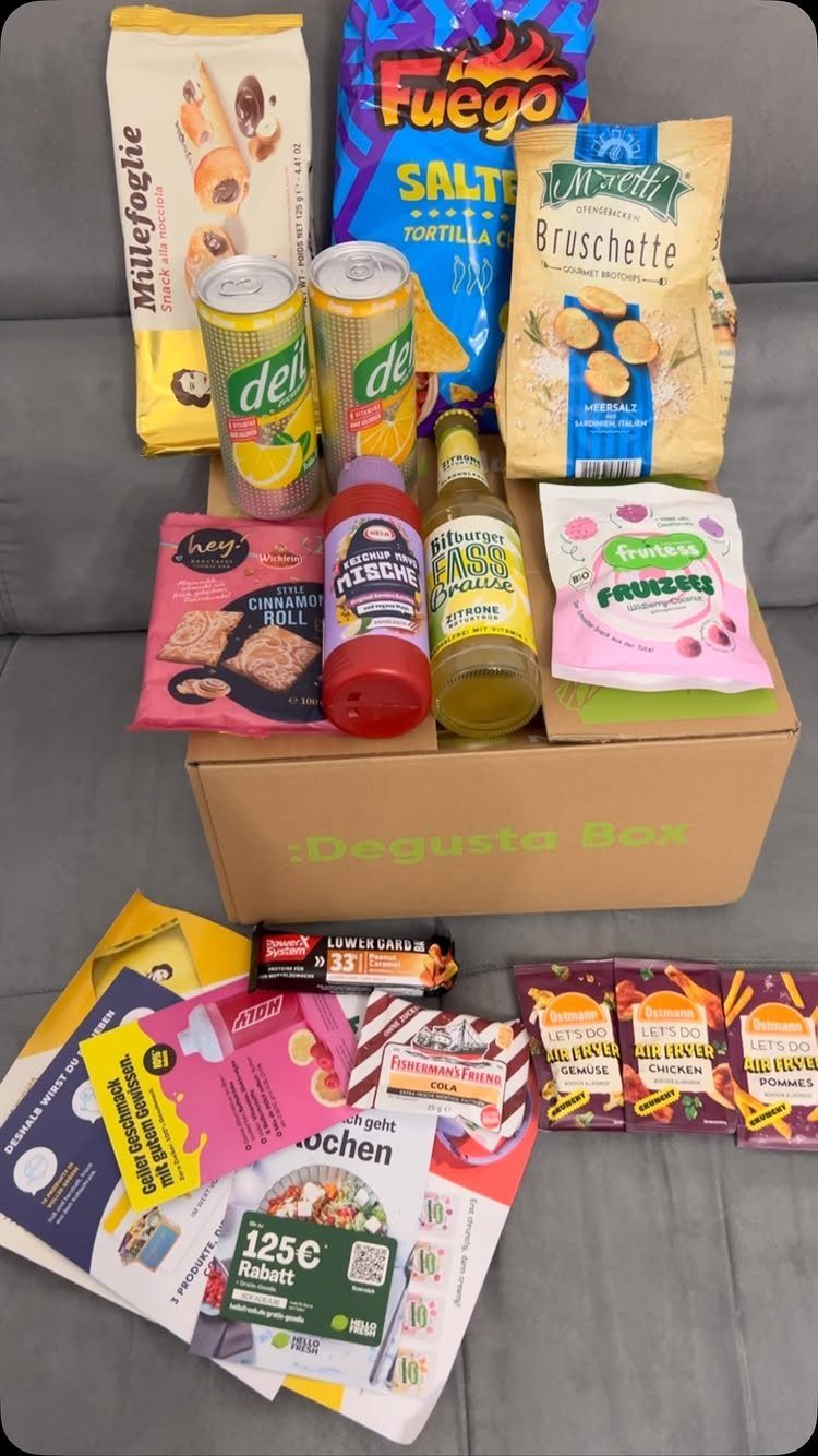 Cardboard snack subscription box filled with assorted chips, drinks, and sweet treats.