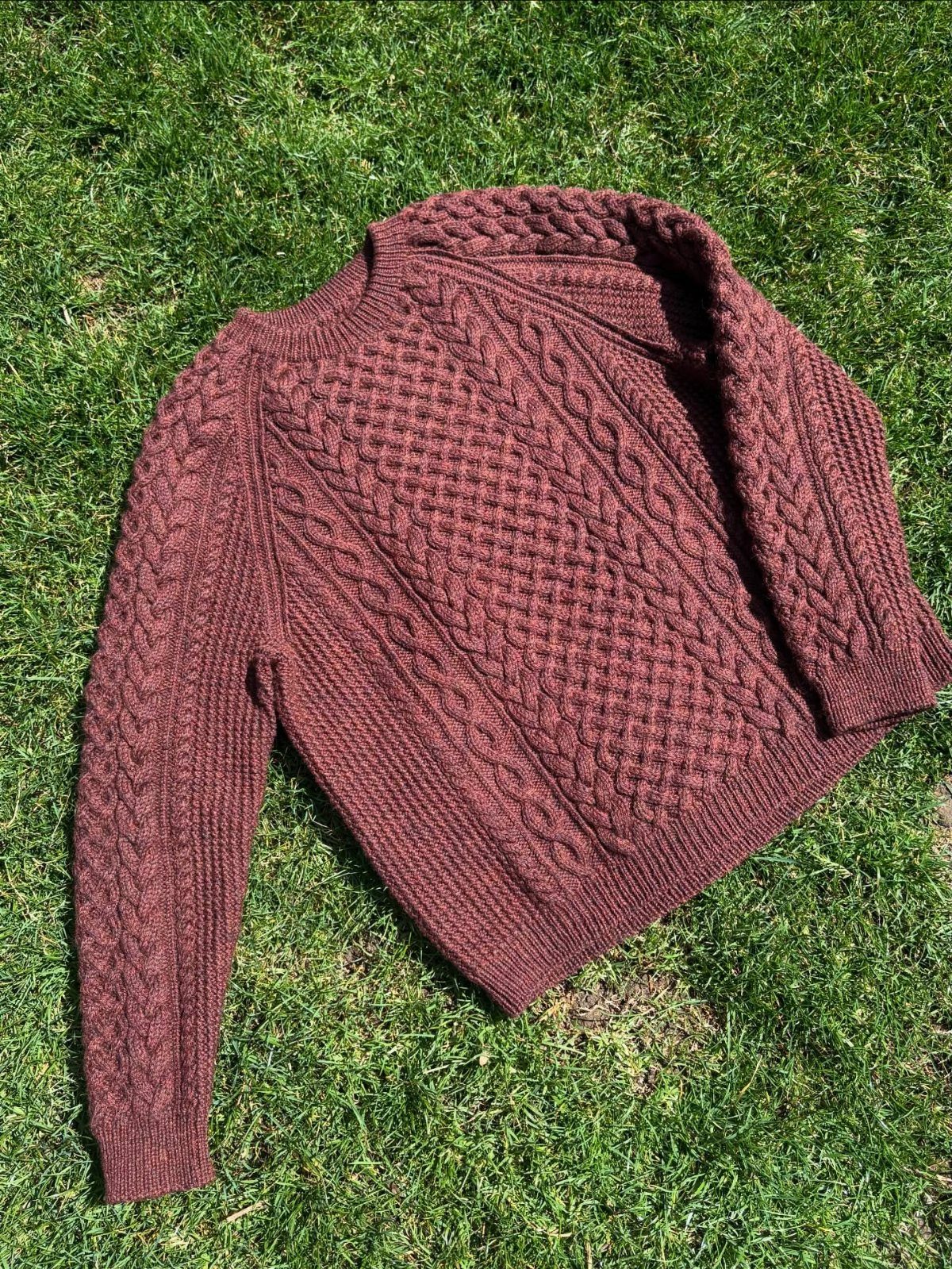 22 Gift Ideas for Brother, From Hoodies to Gadgets 19 Maroon cable-knit sweater laid flat on a lush green grass lawn.